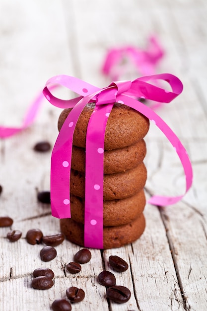 Pila de galletas de chocolate atadas con cinta rosa y granos de café
