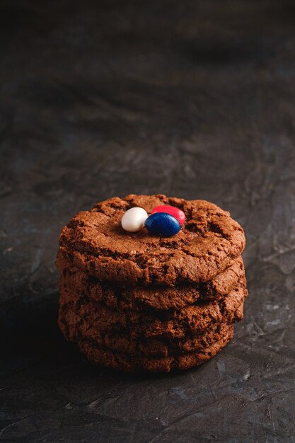 Pila de galletas de chocolate de avena caseras con cereal con jugosas gominolas sobre una superficie negra oscura con textura, ángulo de visión