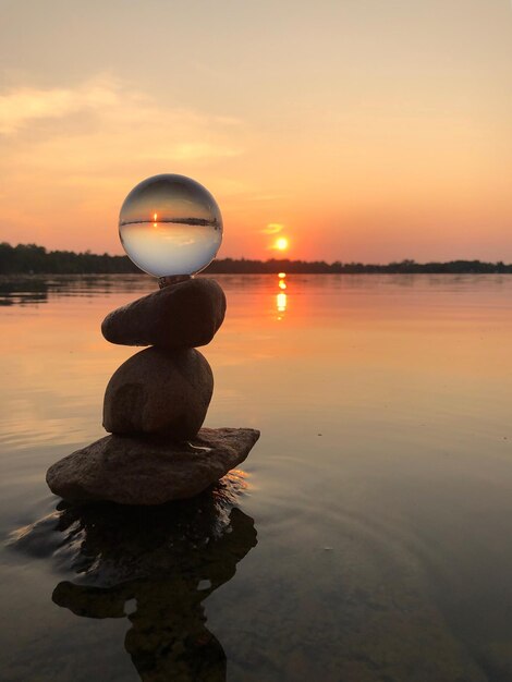 Foto una pila de guijarros en el lago contra el cielo durante la puesta de sol