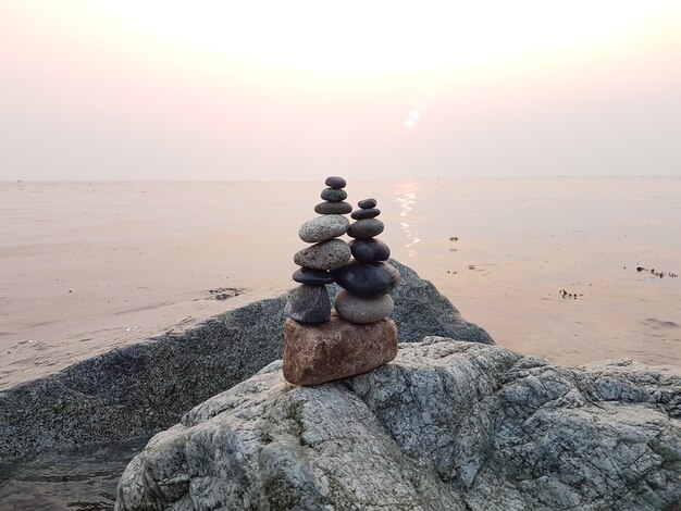 Foto una pila de guijarros en la playa contra el cielo durante la puesta de sol