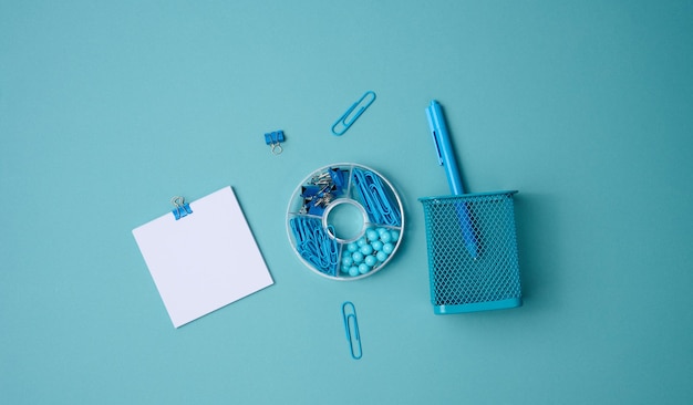 Pila de hojas de papel cuadradas blancas para notas, papelería sobre fondo azul, vista superior