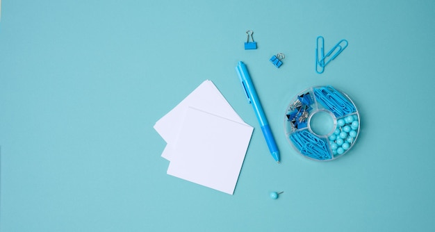 Pila de hojas de papel cuadradas blancas para notas, papelería sobre fondo azul, vista superior