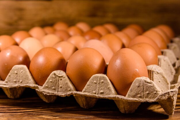 Pila de huevos de gallina en bandeja de papel sobre mesa de madera