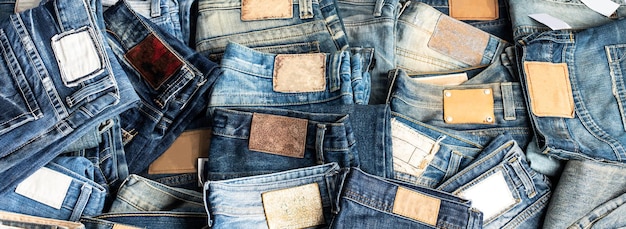 Pila de jeans de varios tonos. Jeans apilados aislados sobre fondo blanco. Bandera de textura de jeans de mezclilla azul con espacio de copia de fondo de diseño de texto. Textura de la moda del dril de algodón de la lona