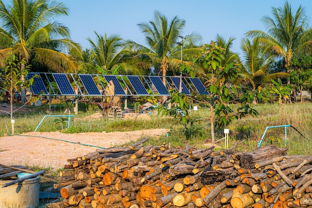 Pila de leña para preparar la tribu del carbón vegetal y el panel solar para la agricultura en un área de casas rurales Campos agrícolas, agroindustria del hogar Estilo rural en Tailandia, alternativa de granja inteligente