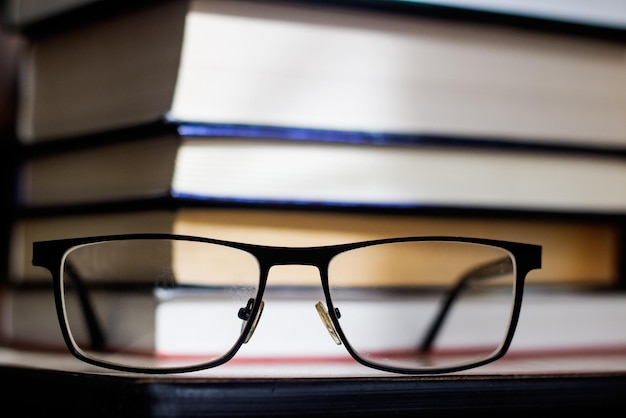 Pila de libros y anteojos de cerca en la oscuridad