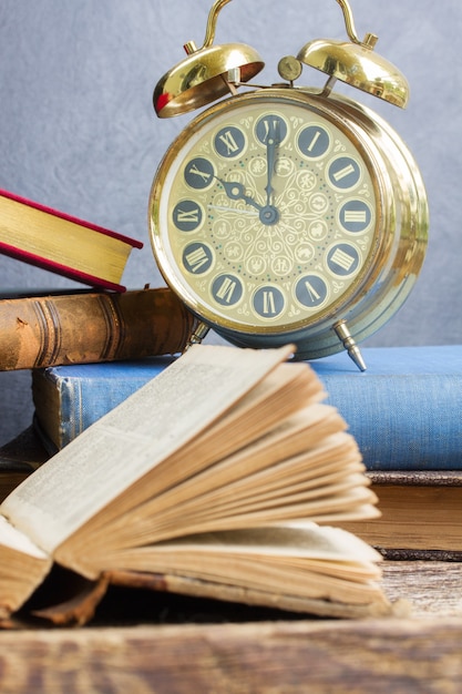Foto pila de libros antiguos con reloj despertador antiguo