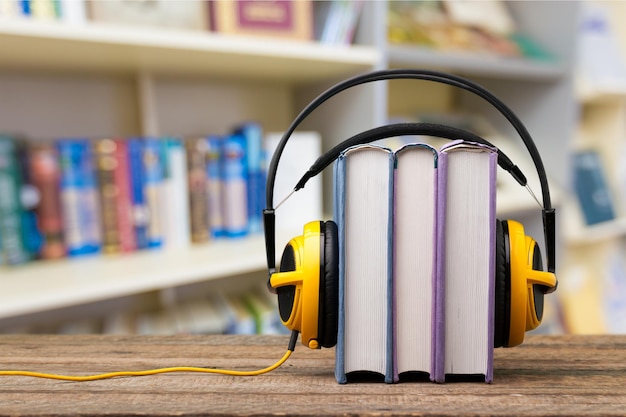 Pila de libros y auriculares en mesa de madera