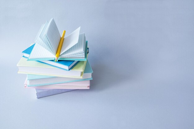 Una pila de libros coloridos y un cuaderno con un lápiz sobre un fondo gris Concepto de regreso a la escuela