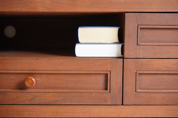 Pila de libros en el estante del armario de madera con fondo oscuro en blanco vacío