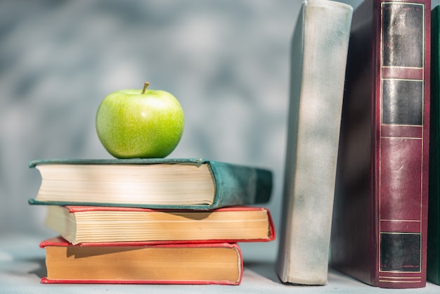 Pila de libros en el estante y manzana verde