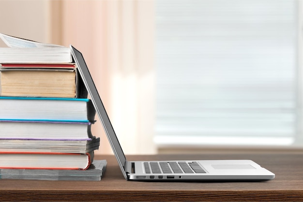 Pila de libros con laptop en la mesa