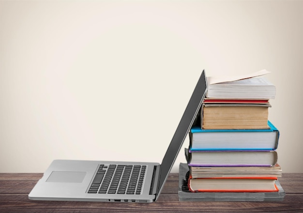 Pila de libros con laptop en la mesa