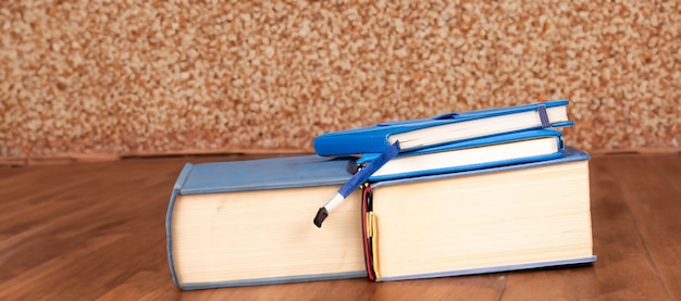 Una pila de libros con una lupa en un escritorio de madera en una biblioteca de información de una escuela o universidad concepto para la educación y el estudio