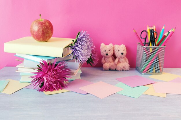 Pila de libros con marcadores de flores frescas, manzana, osos de peluche, lápices, papel, regreso a la escuela