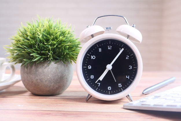 Pila de libros, portátil y reloj en la mesa de cerca