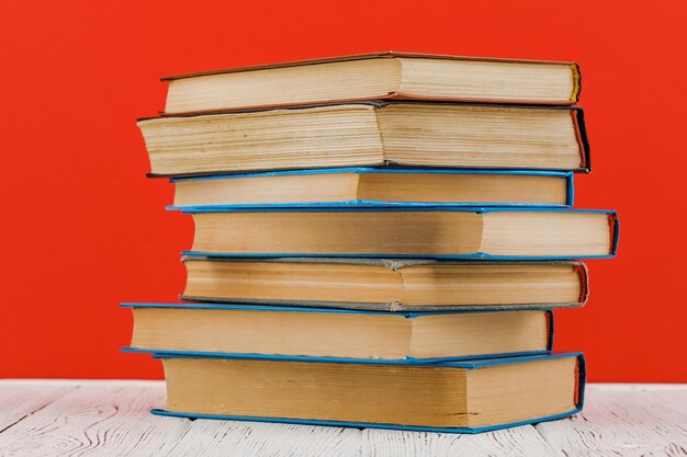 Una pila de libros sobre una mesa blanca sobre un fondo rojo.