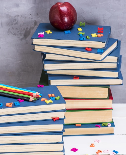 Pila de libros en la tapa azul, lápices de madera multicolores