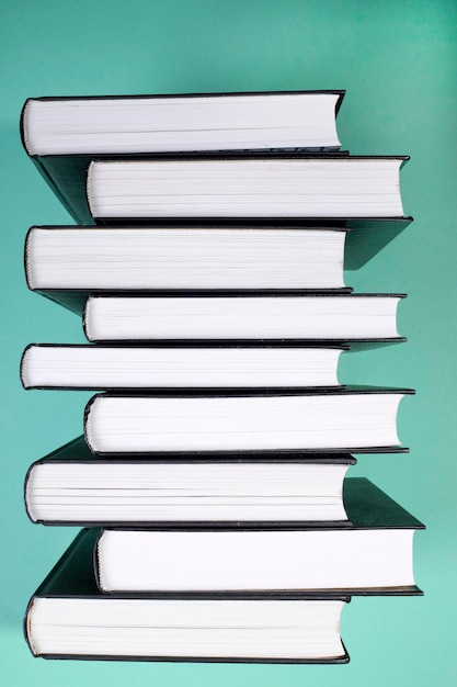 Una pila de libros en una vista lateral de fondo verde