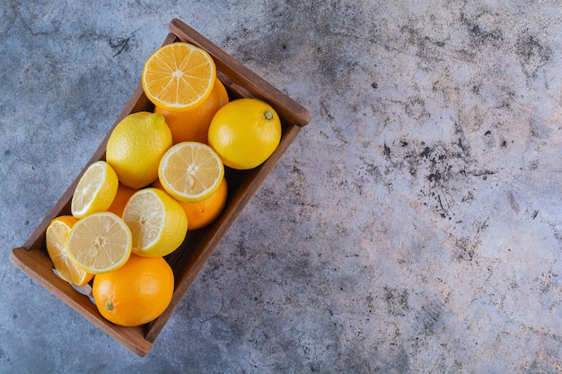 Pila de limones y naranjas orgánicos en caja de madera.