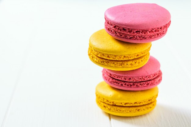 Una pila de macarons rojos y amarillos sobre una mesa de madera blanca