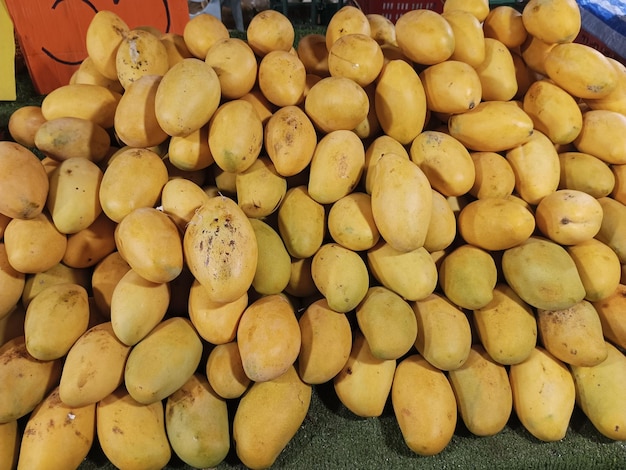 una pila de mangos amarillos con un fondo rojo