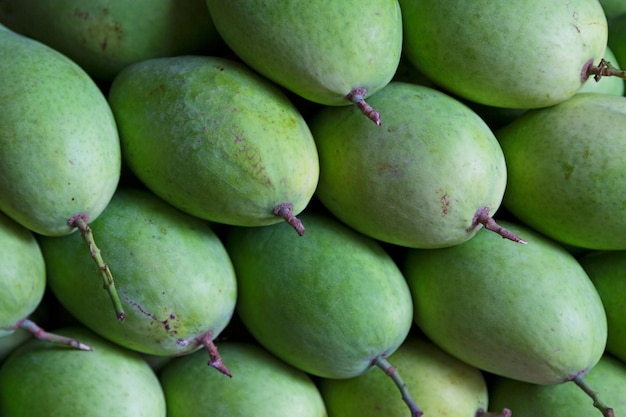 Pila de mangos verdes a la venta en un puesto en el mercado