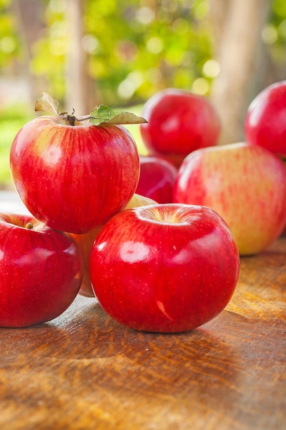 Pila de manzanas en la mesa de madera en el jardín