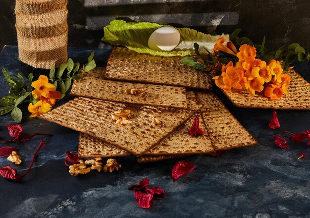 Una pila de matza con flores y nueces como exhibición de comida con los dedos en la mesa