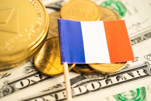 Pila de monedas con bandera de Francia y billetes de dólar estadounidense