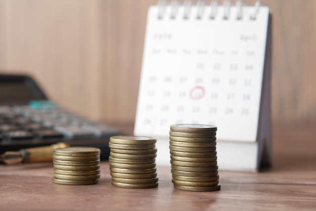 Pila de monedas y calendario en la mesa