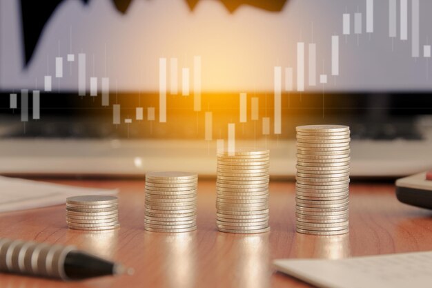 Pila de monedas de dinero y computadora portátil con concepto de inversión financiera de gráfico comercial