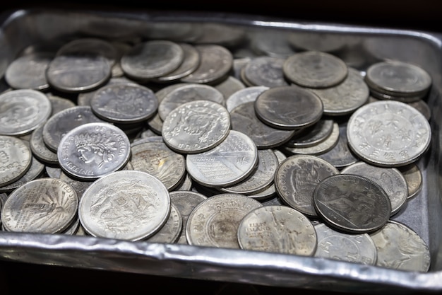 Foto pila de monedas de metal de diferentes denominaciones y diferentes países en caja de metal