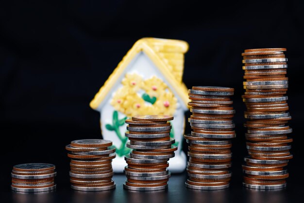 Pila de monedas y modelo de casa sobre fondo blanco concepto de ahorro hipotecario