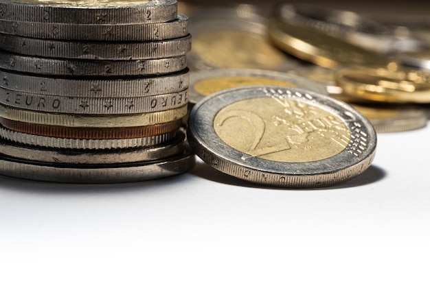 Pila de monedas y moneda de dos euros con enfoque suave