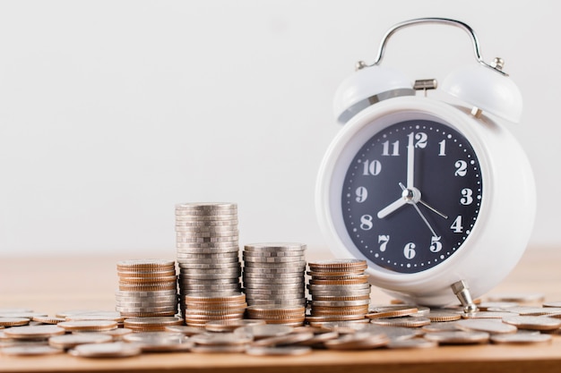 Pila de monedas con reloj para ahorrar dinero concepto