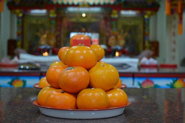 Una pila de naranjas sobre una mesa con un cartel en el fondo.