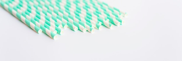 Pila de pajitas de papel a rayas blancas y verdes para fiesta sobre fondo blanco. espacio para texto