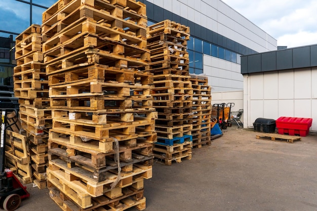 Una pila de palets de madera en un almacén interno Un área de almacenamiento de palets al aire libre bajo el techo junto a la tienda Montones de palets de carga Eurotype en una instalación de reciclaje de residuos