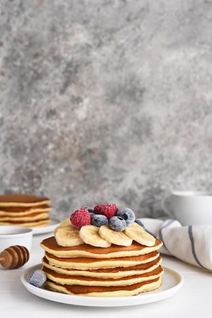 Pila de panqueques con bayas y jarabe en una mesa de cocina para desayunar Buenos días