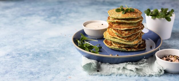 Pila de panqueques de brócoli o espinacas con aderezo agrio de yogur o crema y microgreen