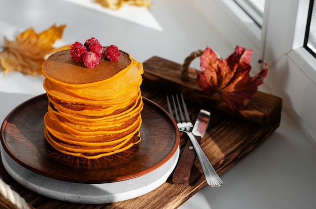 Una pila de panqueques de calabaza con frambuesas.