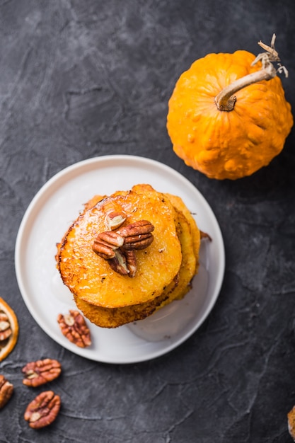 Pila de panqueques de calabaza con salsa de caramelo y nueces pecanas