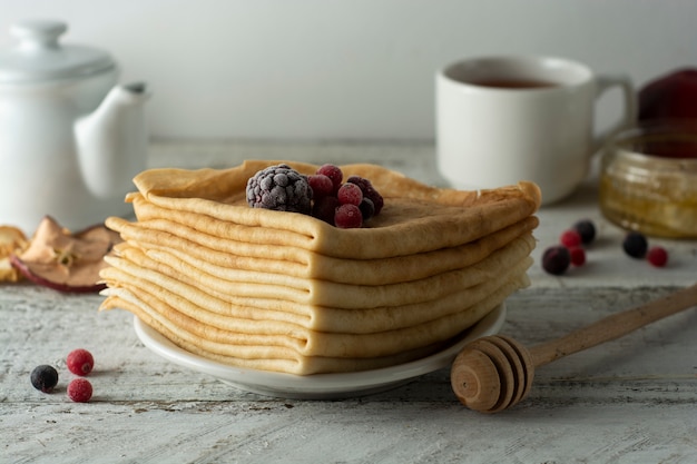 Pila de panqueques finos decorados con fresas y arándanos. Desayuno saludable.