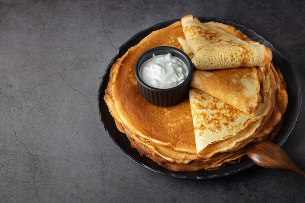 Pila de panqueques finos rusos blini con crema agria fresca