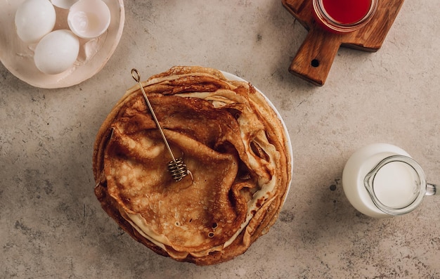 Pila de panqueques finos tradicionales para la semana de panqueques rusos Crepes caseros con mermelada de espino cerval de mar y leche para el desayuno Enfoque selectivo