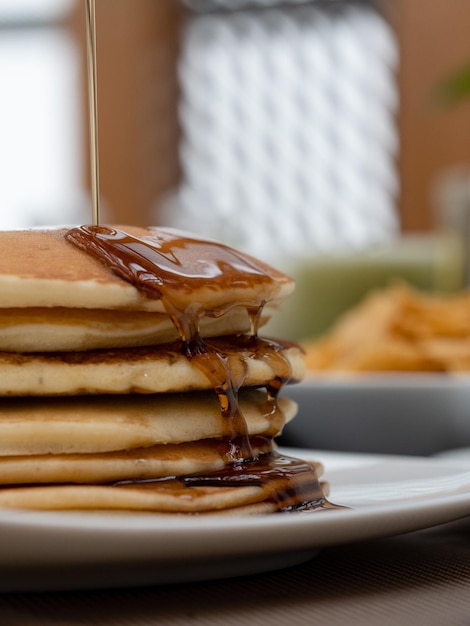 una pila de panqueques con jarabe en ellos y un plato con un plato de pancakes en él