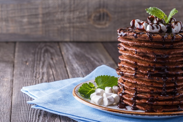 Pila de panqueques con malvavisco y jarabe de chocolate.