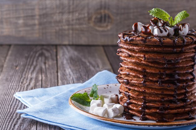 Pila de panqueques con malvavisco y jarabe de chocolate.