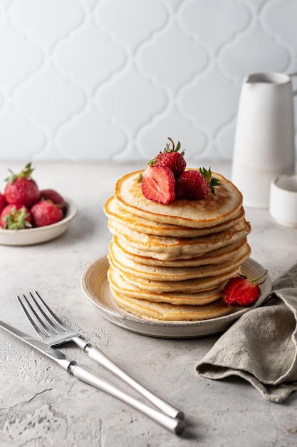 Pila de panqueques con miel, fresas, cuchillo y tenedor Concepto de desayuno casero